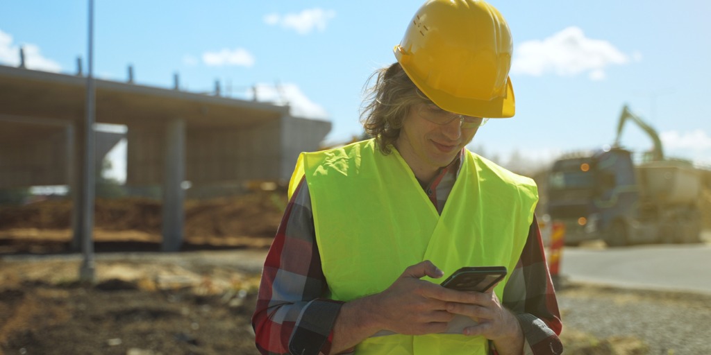 builder writes sms on smartphone at construction site picture id1326076314